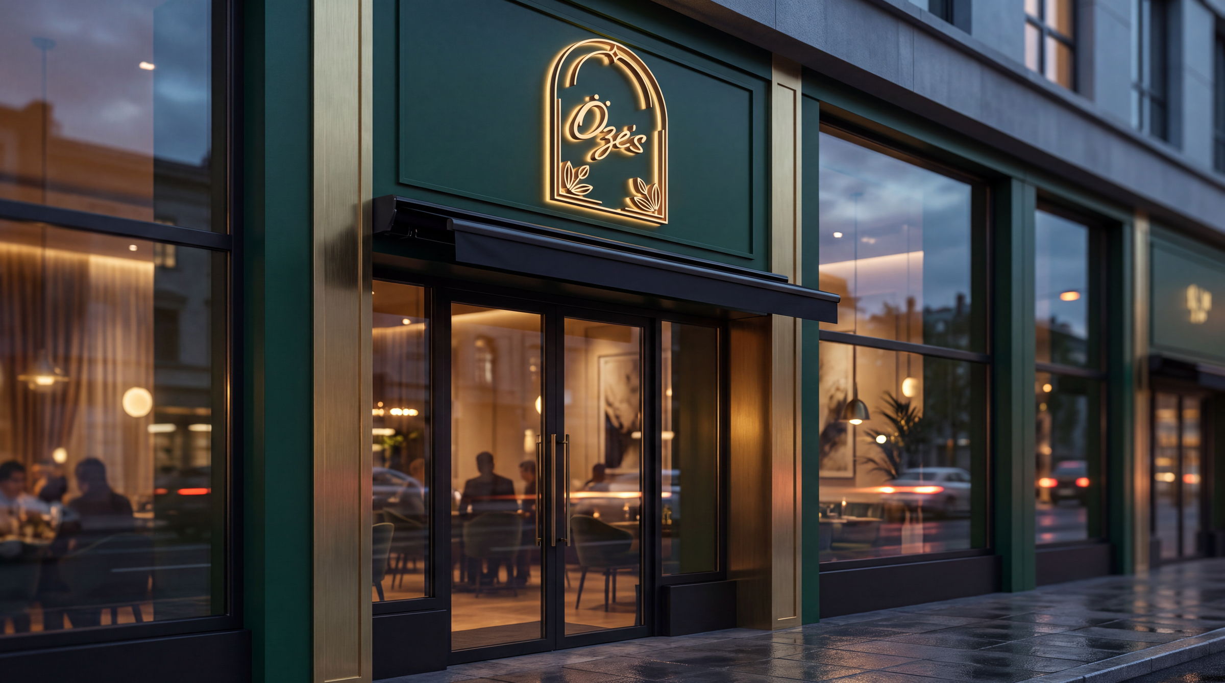 The Öze's Cafe arch neon glowing gold above a deep green storefront at dusk, the lit room visible through tall windows.
